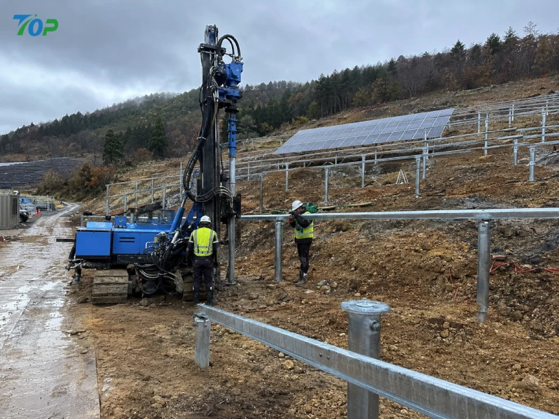 日本の山間部にある太陽光発電所において、油圧機器を用いてスクリュー杭基礎を設置する実際の施工風景